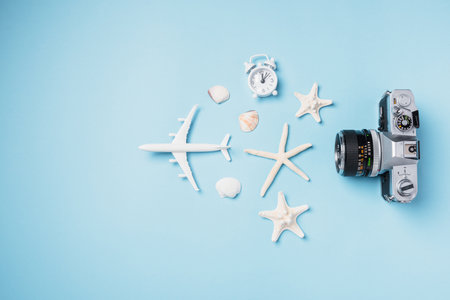Flat lay top view mockup retro camera films, airplane, starfish, shells traveler tropical accessories isolated on a blue background with copy space, Business trip, and vacation summer travel conceptの写真素材