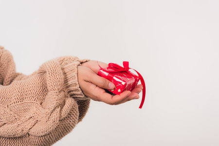 Valentine Day. Female beauty hands holding small gift package box present wrapped paper with ribbon isolated on white background, Christmas, New year, Birthday holiday background conceptの写真素材
