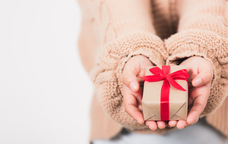 Valentine Day. Woman beauty hands holding small gift package box present wrapped paper with ribbon, Christmas, New year, Birthday holiday background conceptの写真素材