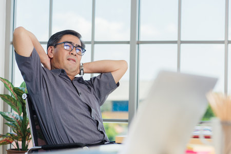 Asian hard senior businessman working with laptop computer has a problem with neck pain. Old man feeling pain after sitting at desk long time, Healthcare and medicine office syndrome conceptの写真素材