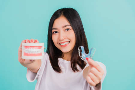 Portrait young Asian beautiful woman smiling holding silicone orthodontic retainers for teeth...