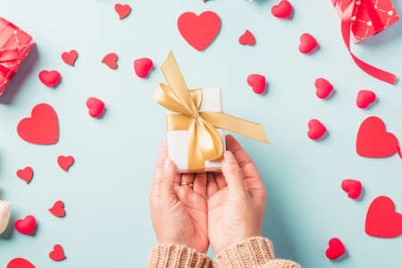 Valentine's day and birthday. Woman hands holding gift or present box decorated and red heart...