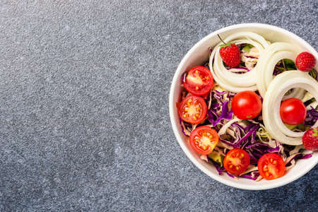 Top view of the healthy colorful salad bowl with tomatoes fresh mixed leaves vegetable in a dish on cement stone table background, Health salad snack diet food weight loss conceptの写真素材