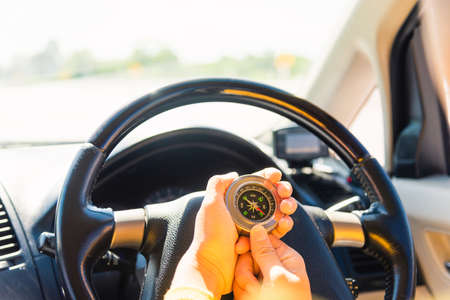 Asian woman inside a car and using compass to navigate while driving the car she find navigation location to go, Transportation and vehicle conceptの写真素材