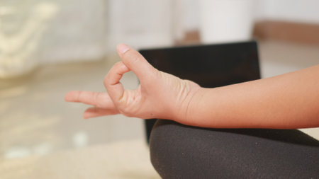 Asian young woman leggings practicing yoga at home sitting in lotus pose on yoga mat for balance, female working out at home in living room. lifestyle sport healthy meditation concept, slow motionの写真素材