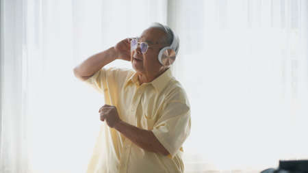 Asian elderly man or grandpa, happy senior retired guy with headphones listening music radio and...