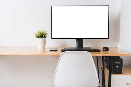 Computer monitor with white blank screen on the business desk with wireless mouse, keyboard at home...