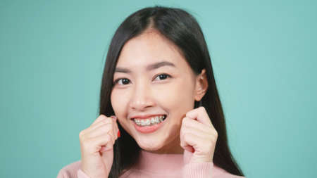Portrait young Asian beautiful woman smiling wear silicone orthodontic retainers on teeth isolated on blue background, Teeth retaining tools after removable braces. Dental hygiene and health conceptの写真素材