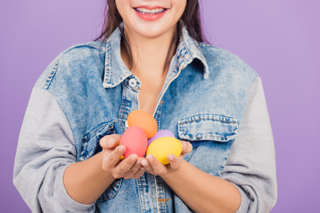 Happy Easter concept. Beautiful young woman smiling wearing rabbit ears and denims hold colorful...