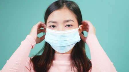 Close up portrait young Asian happy beautiful woman wearing anti virus protection face mask. Female wear sterile medical mask,  outbreak protection healthcare conceptの写真素材