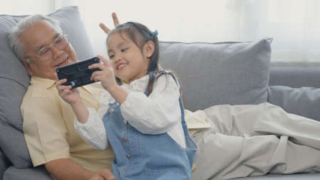 Happy senior grandfather with grandson taking photo by smartphone, old grandpa embracing little...