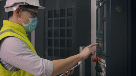 Asian factory worker man operating automated programming CNC milling control machine industry center...