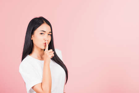 Asian happy portrait beautiful cute young woman smile stand making finger on lips mouth silent quiet...