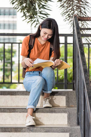 Portrait of Happy young Asian teen woman student sitting during she reading a book at university, Education back to university conceptの写真素材