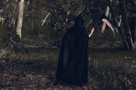 Back woman horror ghost holding reaper in forest, halloween conceptの写真素材