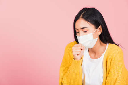 Asian beautiful young woman wearing medical mask protection for prevent infection coronavirus, COVID-19 she cough sneeze, studio shot isolated on pink background, Medical health care conceptの写真素材