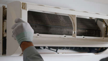Technician service checking and repair air conditioner house indoors on the wall, young man...