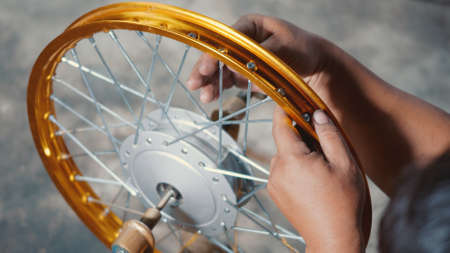 Technician man working motorcycle wheel has spokes weave up on mechanic new steel wheel, Motorcycle...