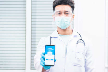 Doctor man in medical mask show app smartphone mobile digital vaccinated passport coronavirus...