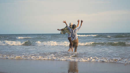Happy Asian active senior man and woman couple lifestyle running to beach and enjoying funny, Romantic elderly enjoy travel summer vacation, plan life insurance at retirement couple conceptの写真素材