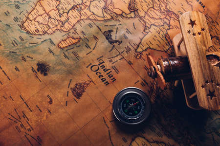 Old compass discovery and wooden plane on vintage paper antique world map background, Retro style...
