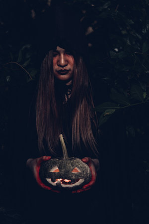 Portrait of woman ghost horror her have pumpkin on hand in forest, halloween day conceptの写真素材
