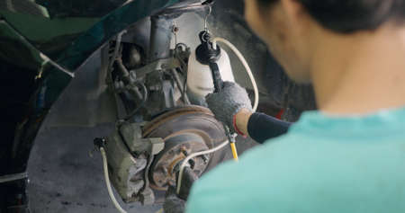 Auto mechanic replacing brake fluid on a vehicle, technician bleed air out of disc brake system in...