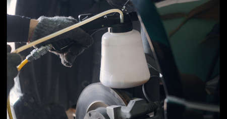 Auto mechanic replacing brake fluid on a vehicle, technician bleed air out of disc brake system in garage workshop, Car repair in a car serviceの写真素材