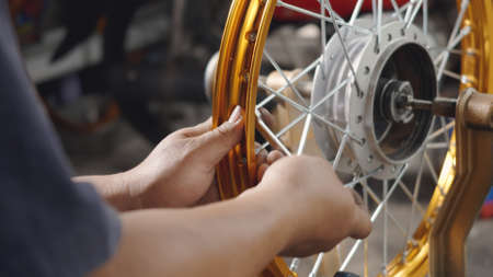 Technician man working motorcycle wheel has spokes weave up on mechanic new steel wheel, Motorcycle...