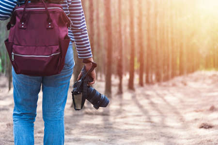 Young woman lifestyle using DSLR camera photographer travel taking photo in forest nature park and...