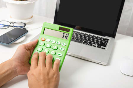 Accountant working and analyzing financial calculating with calculator and laptop computer income-expenditure at office desktop, Business financial and tax systems conceptの写真素材