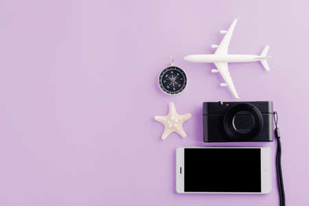 World Tourism Day, Top view of minimal model plane, airplane, starfish, alarm clock, compass and smartphone blank screen, studio shot isolated on purple background, accessory flight holiday conceptの写真素材