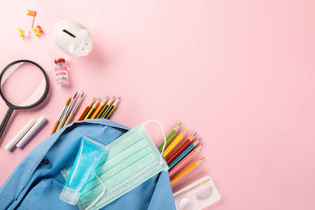 Back to school or college concept. Top view of school supplies stationery, backpack and surgical face mask, isolated on pink background, Back to start education new normal during outbreakの写真素材