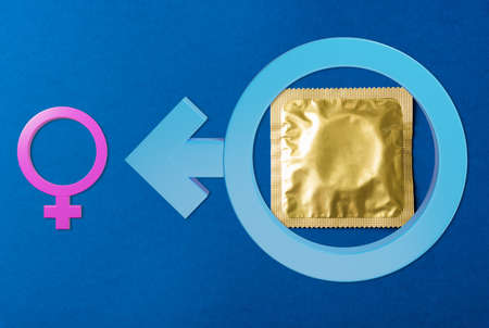World sexual health or Aids day, Top view flat lay condom in wrapper pack and Male, female gender signs, studio shot isolated on a dark blue background, Safe sex and reproductive health conceptの写真素材