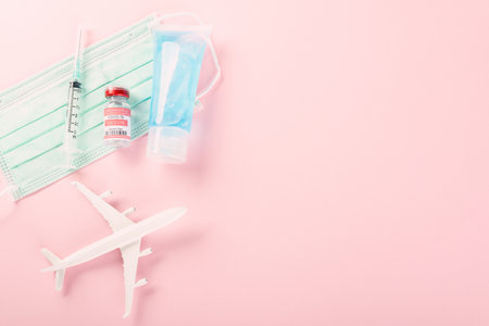 Model plane, COVID-19 coronavirus vaccine vials bottles for vaccination and medical face mask, buy vaccine, tourism worldwide delivery studio shot isolated pink background with copy space for textの写真素材