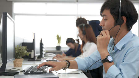 Call center young employee working with headset, Smiling customer support operator team at work...