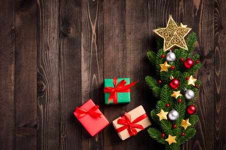 Beautiful Christmas green tree fresh fir branches and ornaments gift box and the star in-studio shot on black wooden background with copy space, New year card conceptの写真素材