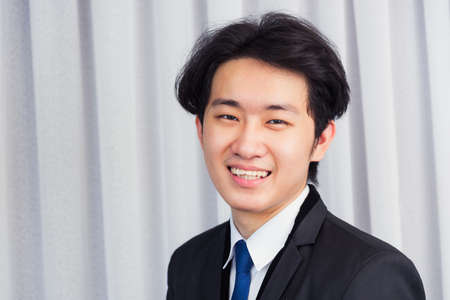 Portrait closeup of happy Asian young handsome manager professional business man laughing confident mature standing in suit smiling looking to camera with copy spaceの写真素材