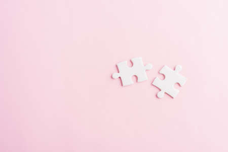Top view flat lay of two paper plain white jigsaw puzzle game last pieces for solve, studio shot on a pink background, quiz calculation conceptの写真素材