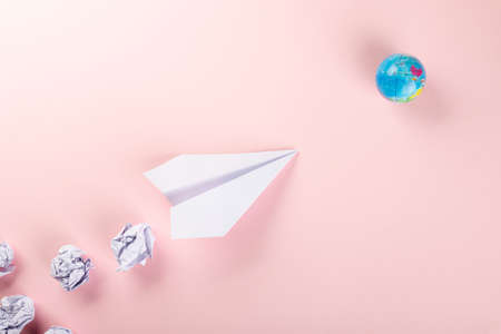 Paper plane tourism. Top view mock up design of airplane travel and globe, education or innovation origami plane, isolated on pink background, world of flight transportationの写真素材