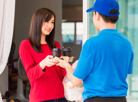 Asian young delivery man in blue uniform he making grocery service giving rice food boxes plastic...