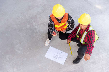 Architect and client discuss help create plan with blueprint of the building at construction site floor. Asian engineer foreman worker man and woman meeting talking on drawing paper project, top viewの写真素材
