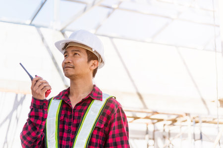 Asian engineer foreman architect worker man working at building construction site talking with...