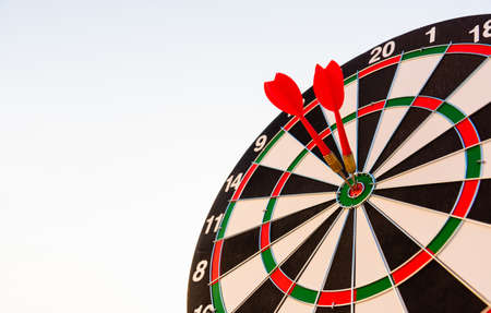 Dart arrow hitting to center on bullseye (bull's-eye) dartboard is the target of purpose challenge business at sunset, expert marketing strategy target, objective financial and goal successの写真素材