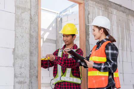 Male industrial builder workers installation process measuring wooden door with measure tape and...