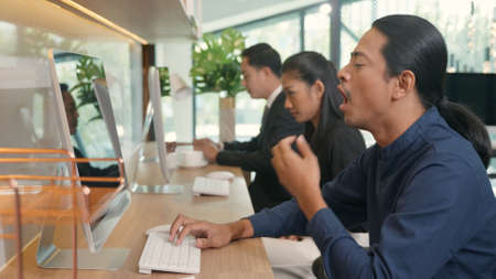 Tired businessteam yawning during working on computer sitting at desk office, business team yawn at workplace feeling no motivation or lack of sleep tired fatigue or overworkの写真素材