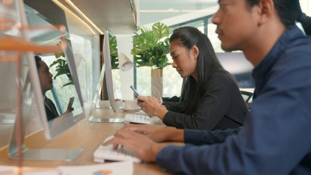 Businesswoman using smartphones on workspace desk in office during team working on computer, Business people holding mobile devices communication technology social network during work timeの写真素材