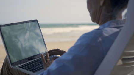 Senior woman relax sitting on chairs enjoying time on beach travel vacation working with laptop...