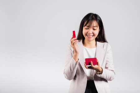 Smiling woman confidence opening a red gift box on palm isolated white background, surprise birthday...
