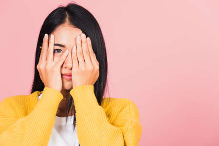 Asian portrait beautiful young woman in depressed bad mood covering face with hands and peering out...